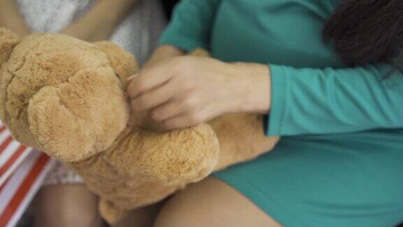 柔软的黄色泰迪熊的特写女性的手拿着礼物孕妇