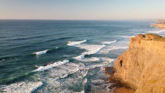 葡萄牙南部一架无人机拍摄到日落时海浪撞击悬崖的海滩