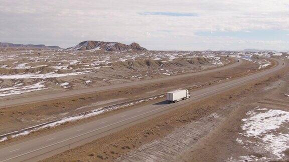 无人机:在阳光明媚的冬日白色卡车在风景优美的州际公路上行驶