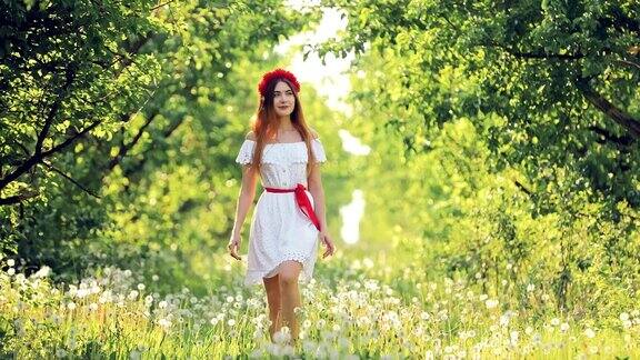 美丽的女孩穿着白色的裙子走过带着蒲公英的草坪晴天在夏天的森林里散步