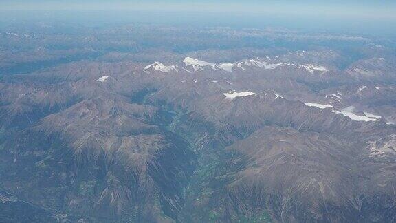 在夏季飞越欧洲阿尔卑斯山冰川的景观从飞机窗口鸟瞰图
