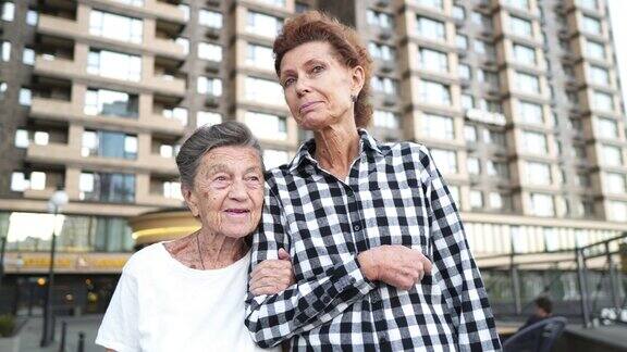 家庭价值观老年妇女与她的老年母亲痴呆拥抱和微笑走在城市快乐的老人和女儿岁精神随着年龄的增长照顾他人的角色也会发生变化