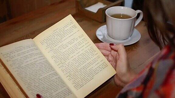 书花白色的杯子和打开的日记本放在木桌上