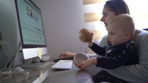 照顾婴儿儿子的中年妇女并在家里使用电脑