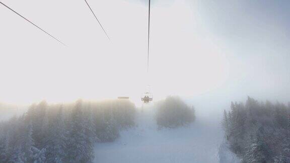 从滑雪椅升降机和雪炮喷洒人工雪在滑雪坡和树木的POV