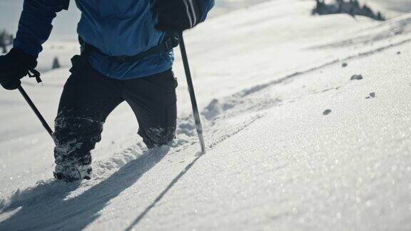 在卡姆尼克-萨维贾阿尔卑斯山脉的一个山坡上一名山地徒步旅行者在刚下过雪的地方跋涉