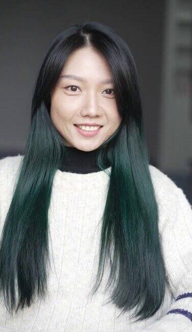 一个绿色头发的年轻亚洲女人在镜子里梳头发