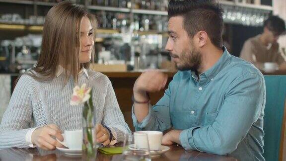 迷人的年轻男子和女子坐在舒适的咖啡店聊天