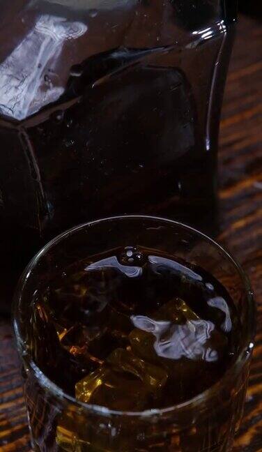 冰块掉进棕色木头上的威士忌酒杯里