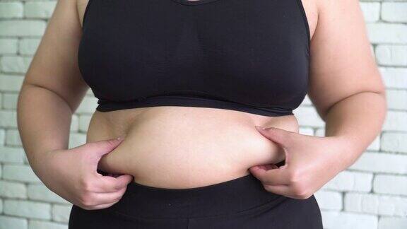 泰国超重妇女的手在运动衣服触摸她的肚子与感觉无聊
