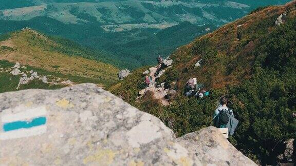 一群背着背包的游客和孩子们沿着山上的石头小径下山