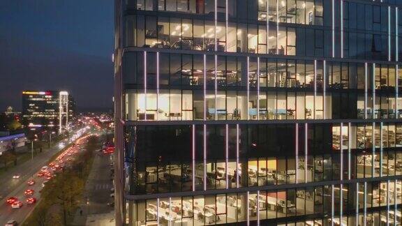 在一座现代化摩天大楼里一架无人机对着办公人员工作到很晚的办公室的夜窗射击