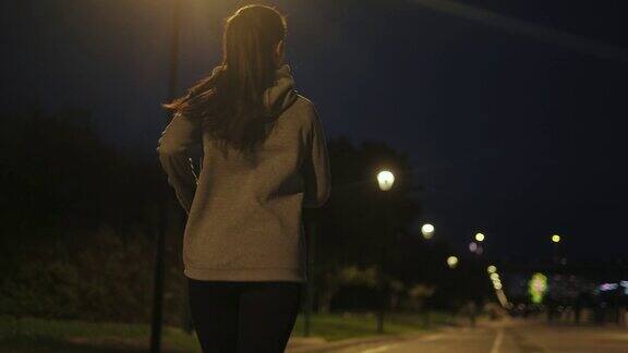 年轻女孩穿着运动服在夜色中奔跑女运动员沿着堤岸慢跑后视图
