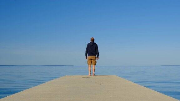 克罗地亚亚得里亚海的帕格岛一名男子走在码头上观察背景中的地平线