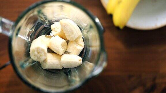 手在搅拌机中加入新鲜香蕉准备水果冰沙