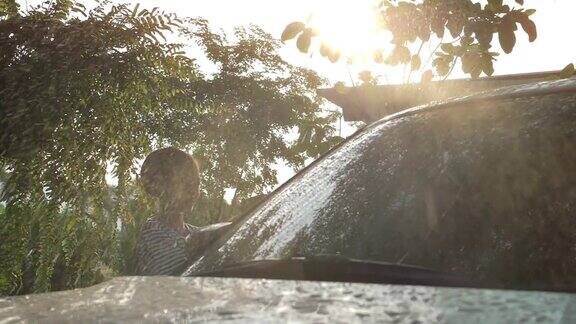 快乐的亚洲女孩在家里洗车溅水和阳光:慢镜头拍摄