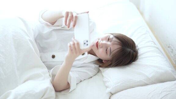 一个女人在床上操作智能手机
