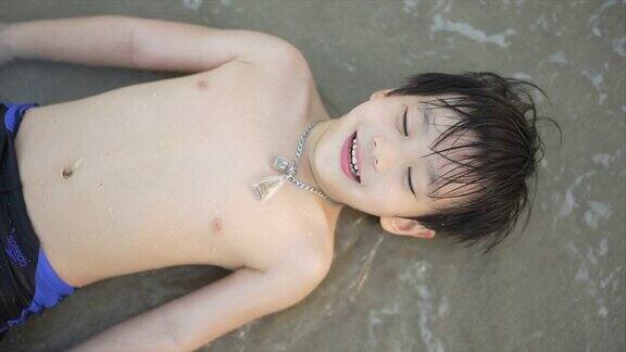 慢镜头拍摄的亚洲男孩在沙滩上享受和玩海和沙子