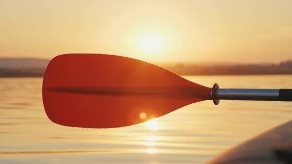 橘色的划桨划桨水滴慢慢滴在平静的海面上慢镜头映衬着夏日灿烂的太阳金色的日落镜头光晕运动的爱好放松