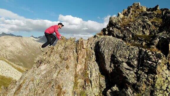 一个年轻人爬上高山上的岩石脊