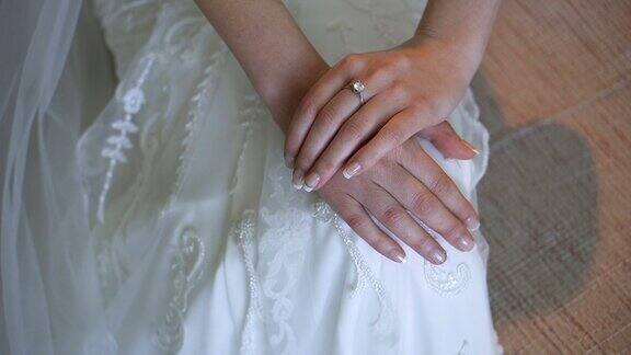 新娘的手与戒指在裙子的蕾丝背景