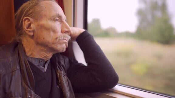戴眼镜的老人在火车上旅行向窗外望去的特写镜头