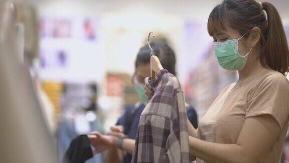 两个亚洲妇女戴着防护口罩在服装店购物