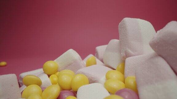 粉红色背景上孤立的糖果和棉花糖