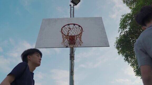 低角度Z一代亚洲中国少年男孩挑战球员并在周末早上和朋友一起练习篮球