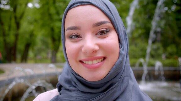 特写漂亮的穆斯林学生戴着头巾微笑真诚和高兴地站在喷泉附近