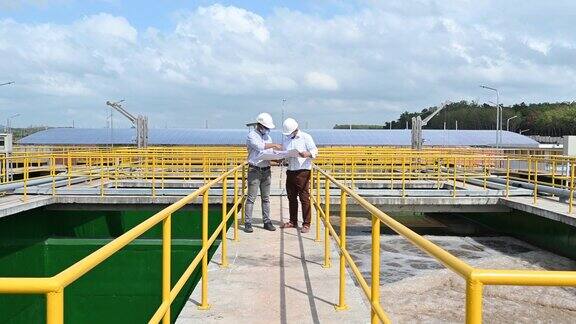 两位东南亚工程师在污水处理厂讨论设计图