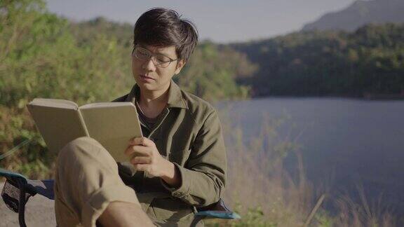 一个年轻人在湖边露营时看书的照片