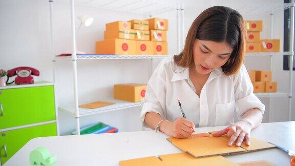 东南亚年轻女性企业家在她自己的工作中检查包裹盒子在家里购物网上业务