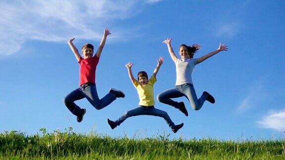 快乐的一家人在碧绿的草山上跳跃映衬着蓝天