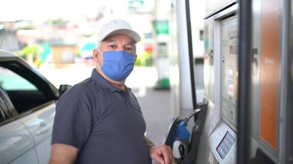 一位戴着面罩的老人在加油站给一辆车加油
