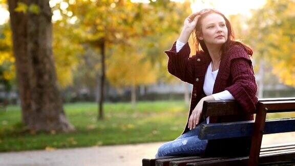 在公园长椅上享受秋天的女人