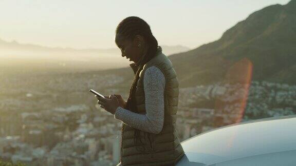 一段4k视频一名迷人的年轻女子独自站在日落时分使用手机