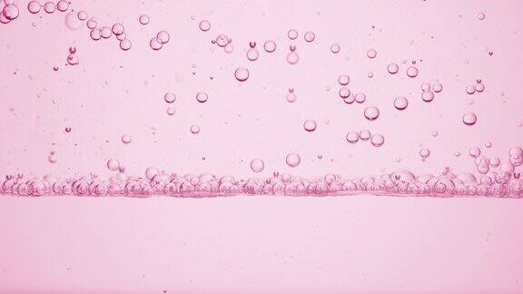 小的透明气泡向下到粉红色背景的表面