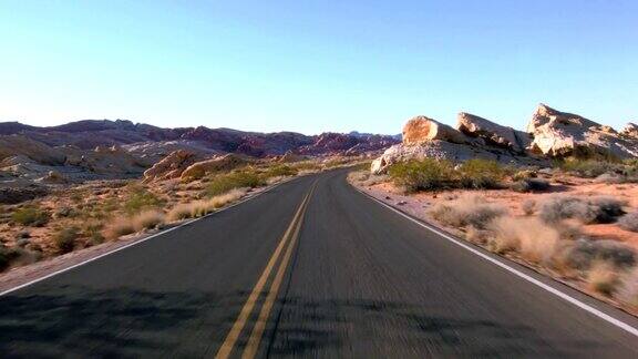 驾驶美国:汽车驾驶的观点通过美丽的沙漠景观在一个空的道路通过火谷内华达州