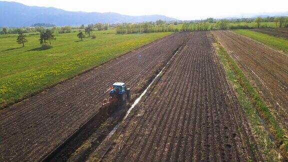 空中农民在一个蓝色拖拉机犁地在美丽的绿色国家