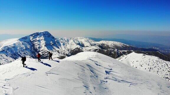 无人机拍摄成功的登山队伍在冬季在高海拔雪山峰顶的山脊上排排攀登