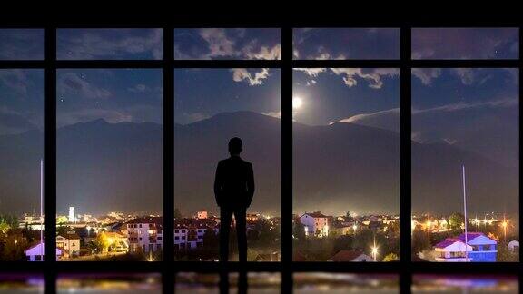 这个男人站在城市夜景的全景窗旁时间流逝