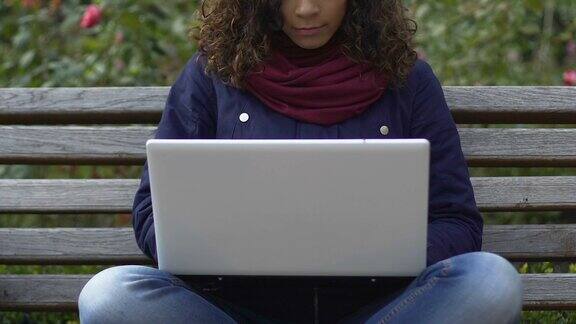 黑白混血的女性自由职业者在公园的笔记本电脑上工作自由职业电子商务
