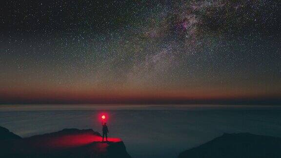 雄鸟拿着燃烧着的烟火棒站在星空的背景上