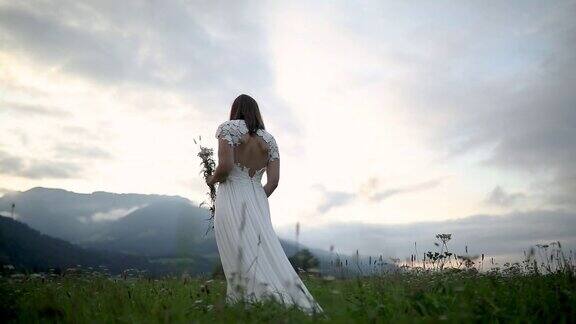 年轻的新娘走在大自然在美丽的一天与婚纱