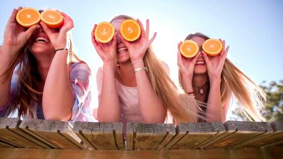 十几岁的女孩朋友们拿着橘子做眼睛