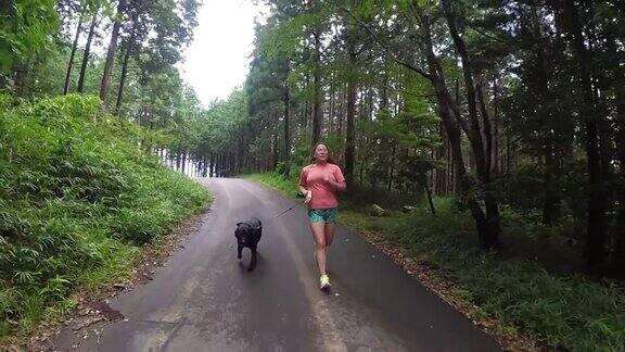 一个女人在森林路上带着狗奔跑