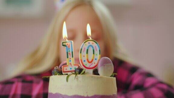 小女孩吹灭彩色蜡烛与数字10在生日蛋糕在慢动作十岁的女孩庆祝生日
