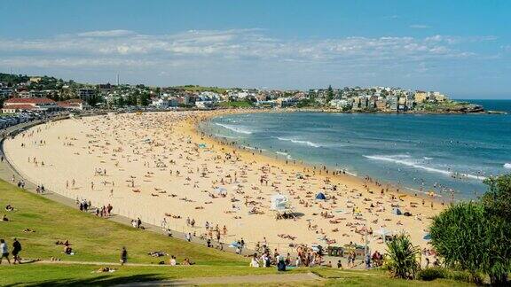 在澳大利亚新南威尔士州悉尼的夏季周末人们在阳光下参观标志性的邦迪海滩放松