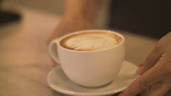 咖啡师把准备好的咖啡卡布奇诺杯放在咖啡馆的桌子上